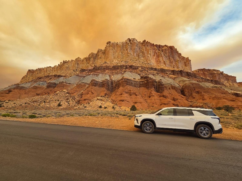 White SUV parked along the Scenic Drive in Capitol Reef National Park under dramatic wildfire smoke during a Utah road trip.